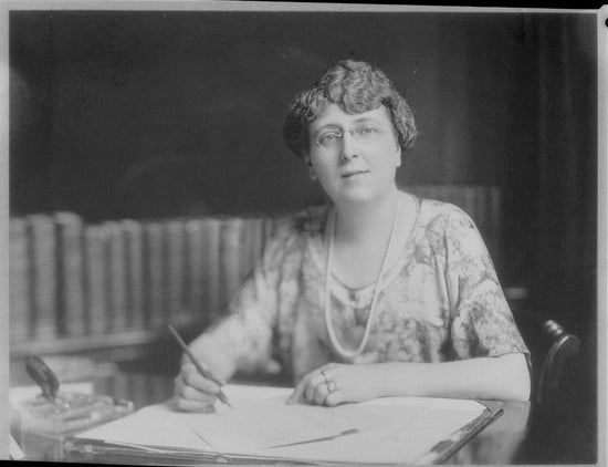 Portrait of author Luch Maud Montgomery sat at her writing desk with a pen in hand